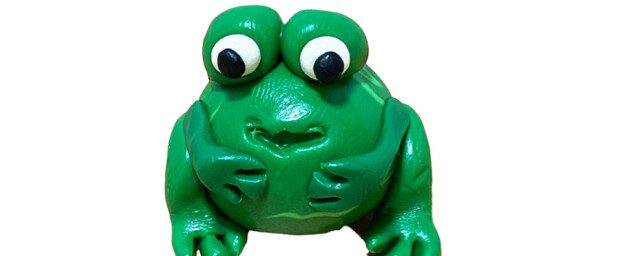 A small caricature model of a frog, possibly made from clay or plaster.