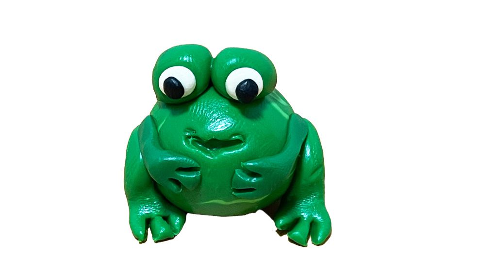 A small caricature model of a frog, possibly made from clay or plaster.