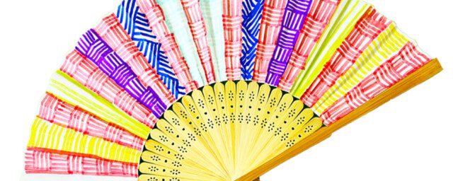 An open fan made from wood at the bottom and paper at the top which has been decorated using red, yellow, purple, light blue and dark blue pens in a hatching design.