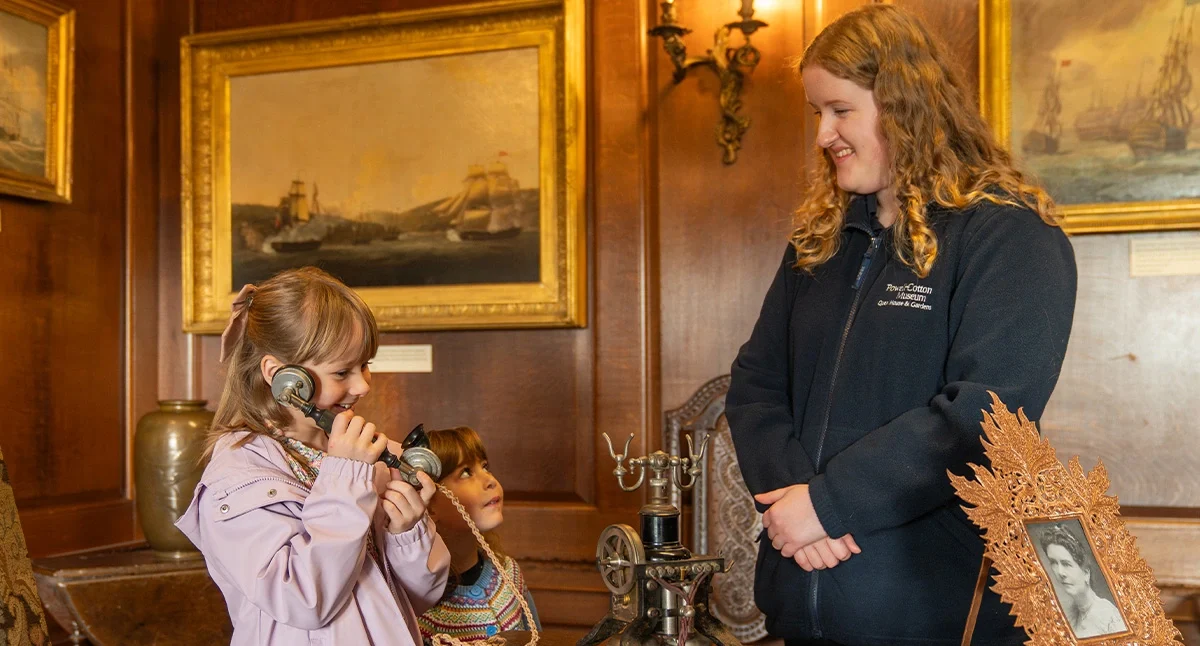 Young girl on an old style phone as a woman looks on